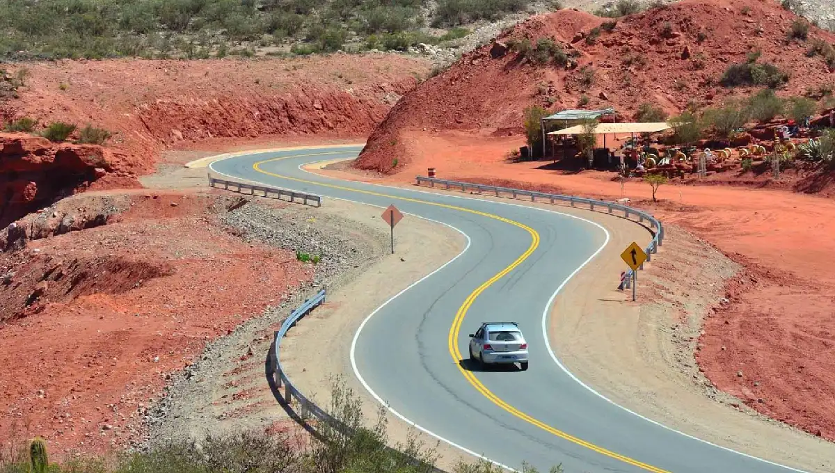 Vista panorámica de una carretera con auto andando y montañas alrededor