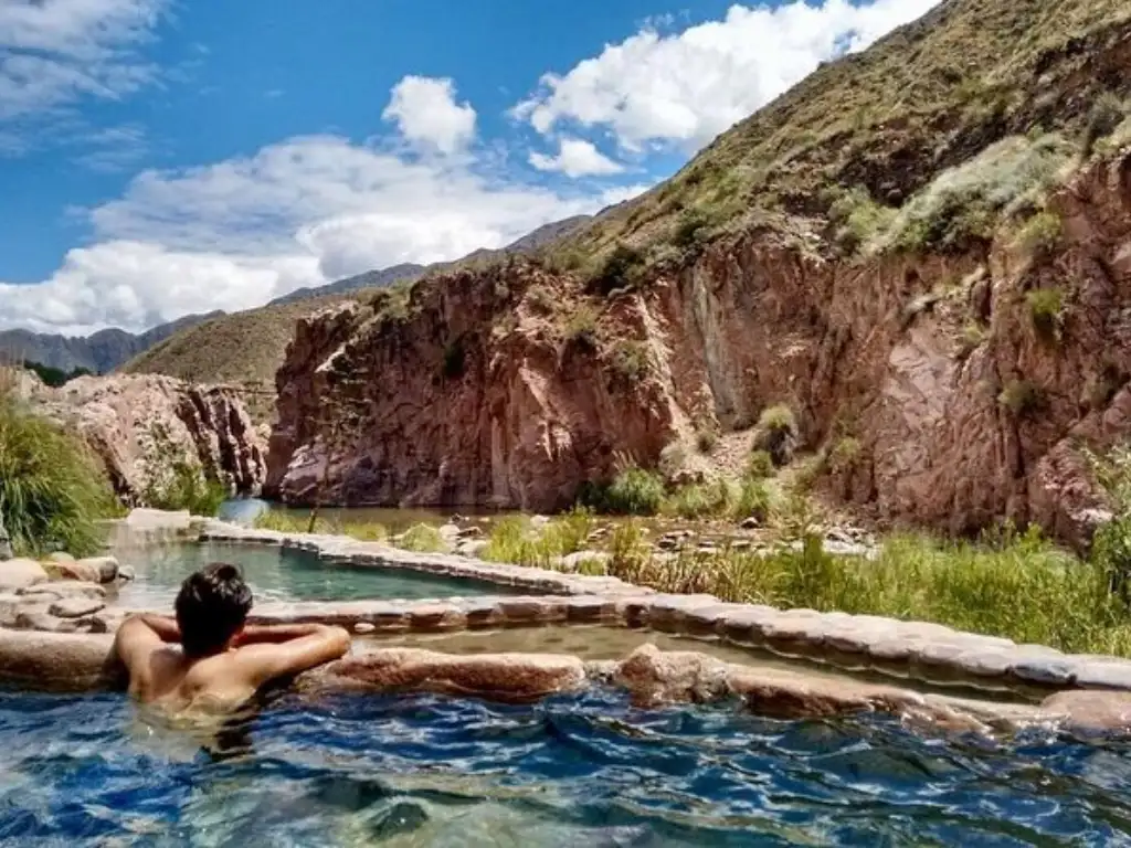 Hombre nadando en las Termas de Cacheuta rodeado de montañas