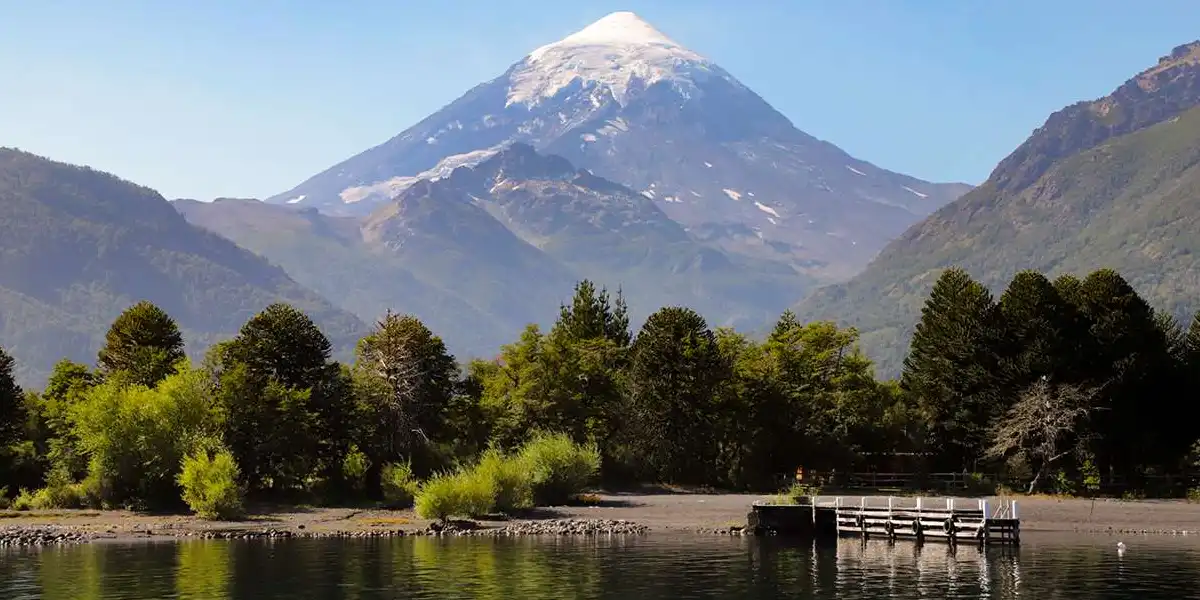 Lago con árboles y montañas en el fondo