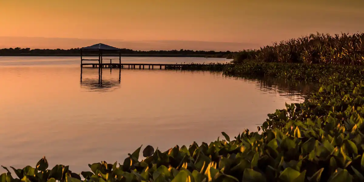 Muelle en el medio del agua con atardecer de fondo